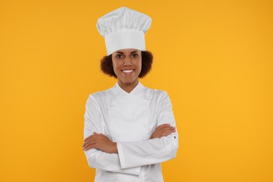 Photo of Portrait of happy female chef in uniform on orange background