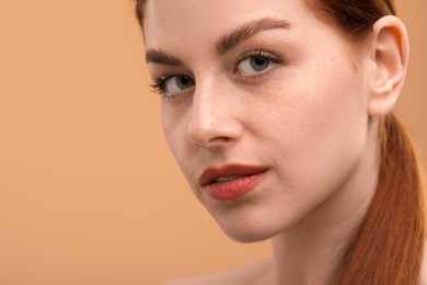 Portrait of beautiful woman with freckles on beige background, closeup. Space for text