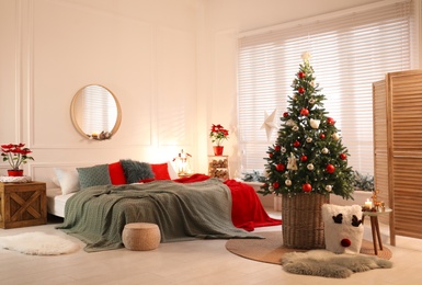 Photo of Beautiful decorated Christmas tree with fairy lights in bedroom. Interior design