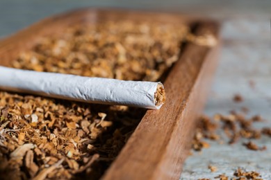 Photo of Hand rolled cigarette and tobacco on table, closeup. Space for text