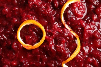 Tasty cranberry sauce with citrus zest as background, top view