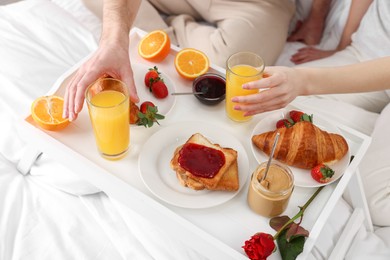 Photo of Couple eating tasty breakfast on bed, above view