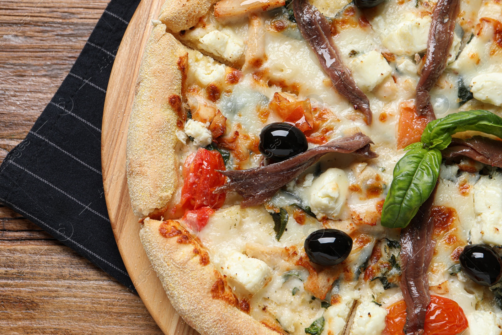 Photo of Tasty pizza with anchovies, basil and olives on wooden table, top view