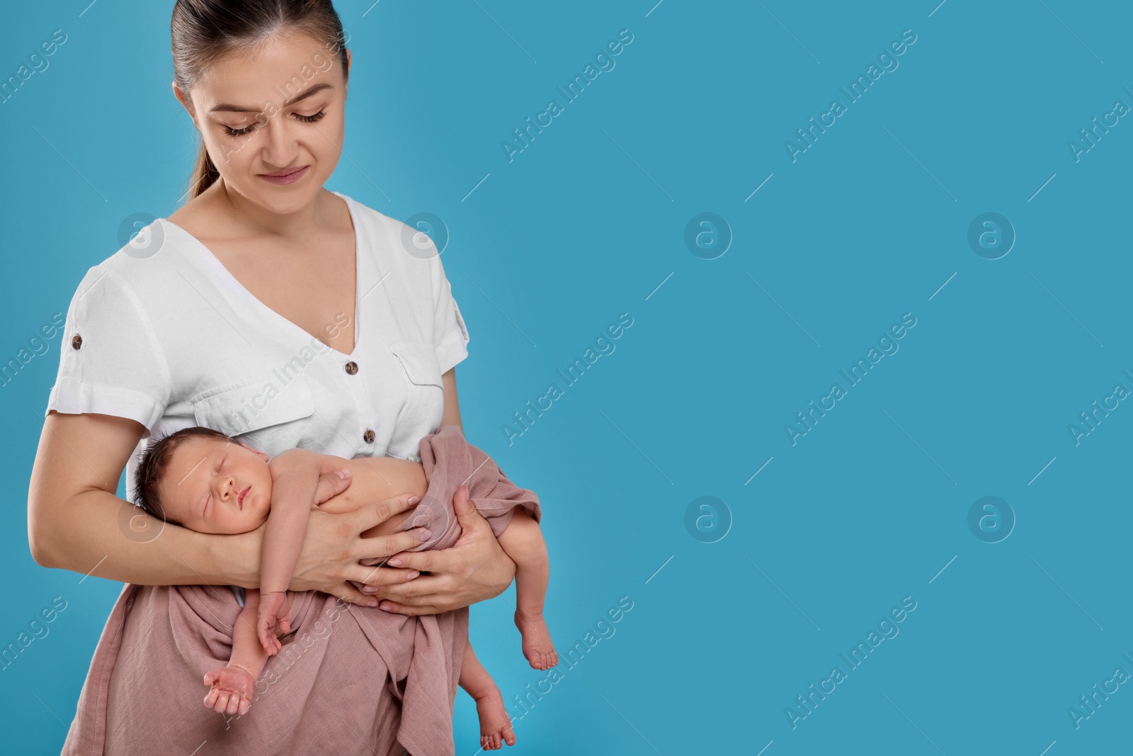 Photo of Mother with her cute newborn baby on light blue background. Space for text