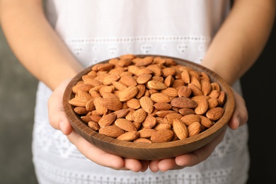 Photo of Woman holding bowl with organic almond nuts, closeup