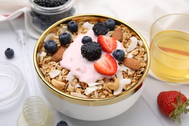 Photo of Tasty granola, yogurt and fresh berries in bowl on white table, closeup. Healthy breakfast