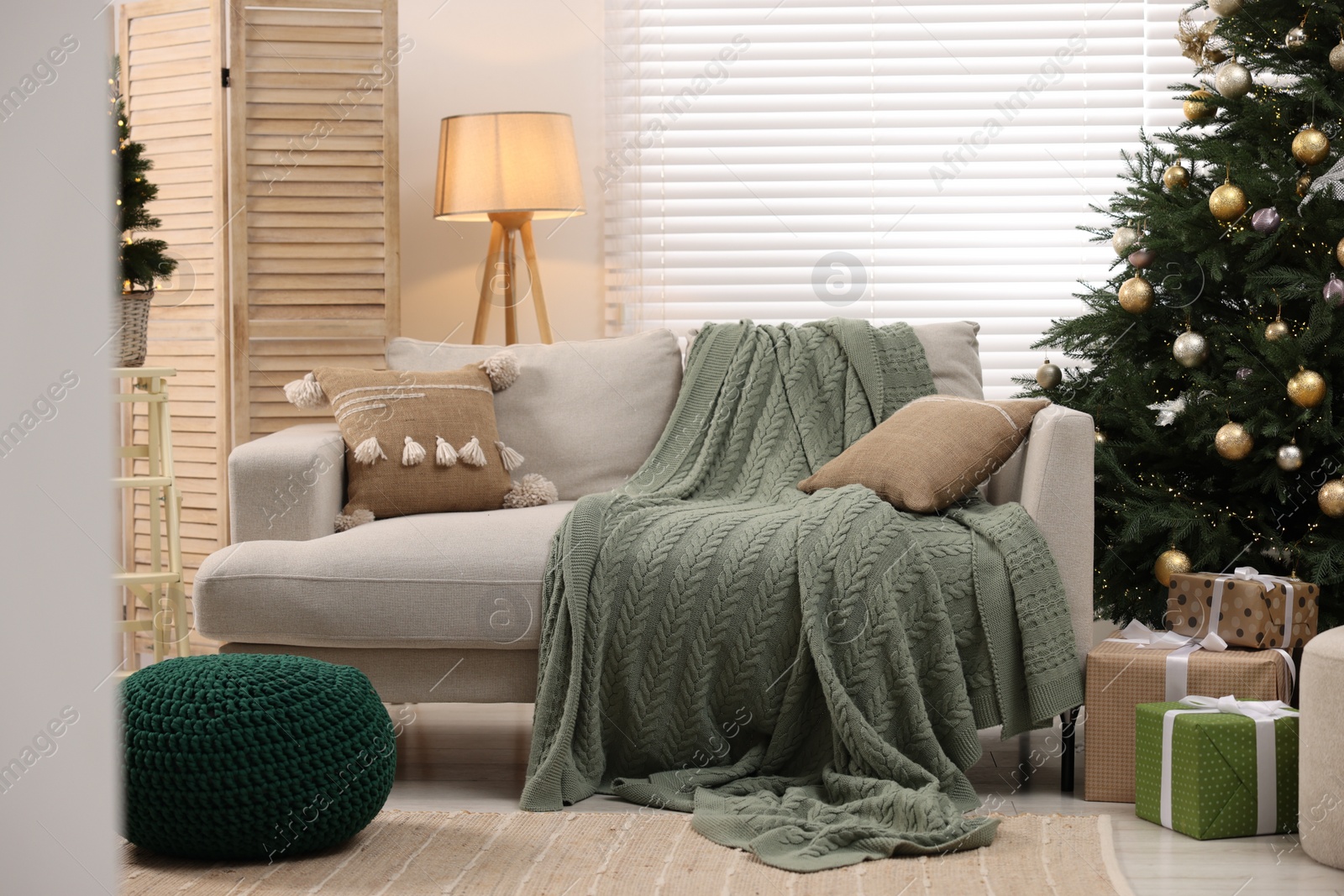 Photo of Sofa near Christmas tree in room. Festive interior design