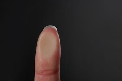 Woman pressing control glass of biometric fingerprint scanner on dark background, closeup. Space for text