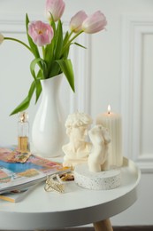 Photo of Different beautiful candles and tulips on white table. Stylish decor