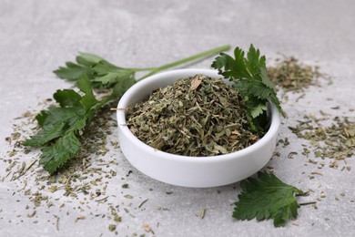 Photo of Dried parsley and fresh leaves on light grey table, closeup