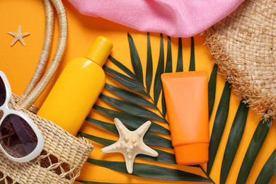 Photo of Flat lay composition with sun protection products and beach accessories on orange background