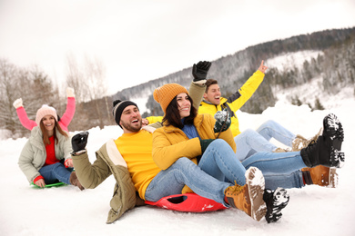 Group of friends having fun and sledding on snow. Winter vacation