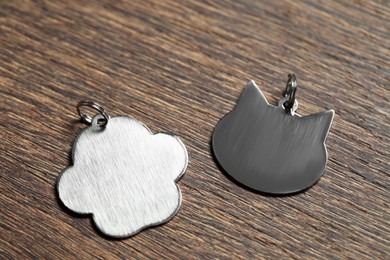 Photo of Silver pet tags on wooden table, flat lay. Space for text
