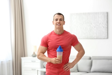 Photo of Athletic young man with protein shake at home