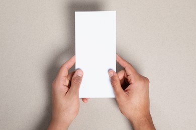 Photo of Man holding flyer on grey background, closeup. Mockup for design