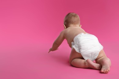 Cute baby in dry soft diaper crawling on pink background, back view. Space for text