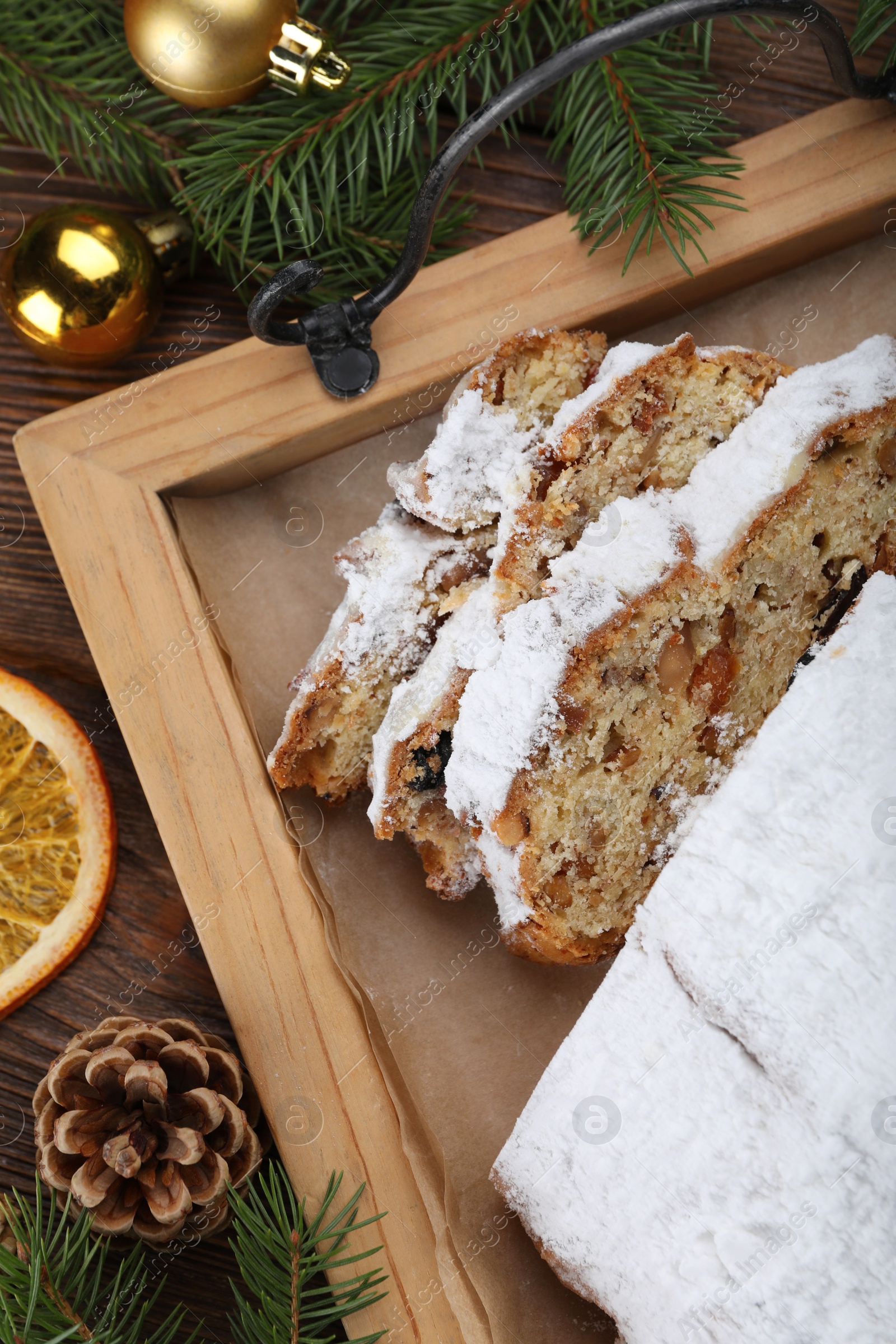 Photo of Traditional Christmas Stollen with icing sugar on wooden table, flat lay