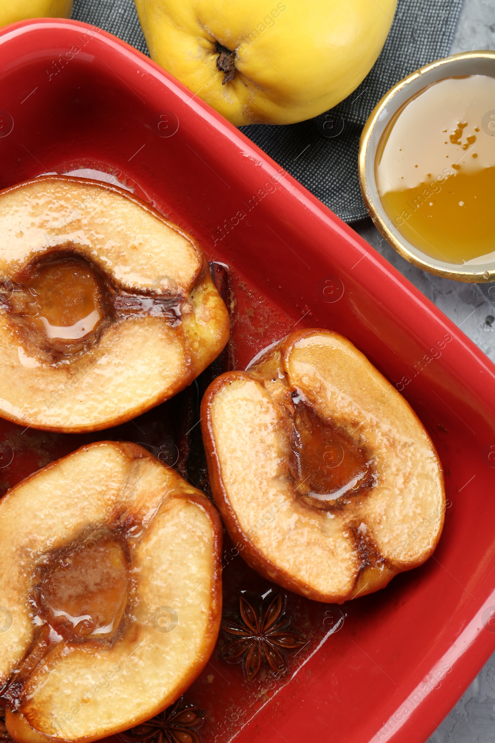 Photo of Tasty baked quinces with honey in dish on grey textured table, flat lay