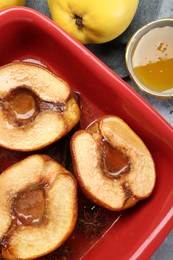 Tasty baked quinces with honey in dish on grey textured table, flat lay