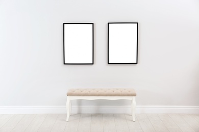 Photo of Frames with empty canvases on wall and bench in modern art gallery. Mockup for design