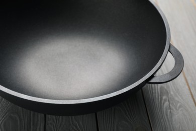 Photo of Empty iron wok on grey wooden table, closeup. Chinese cookware