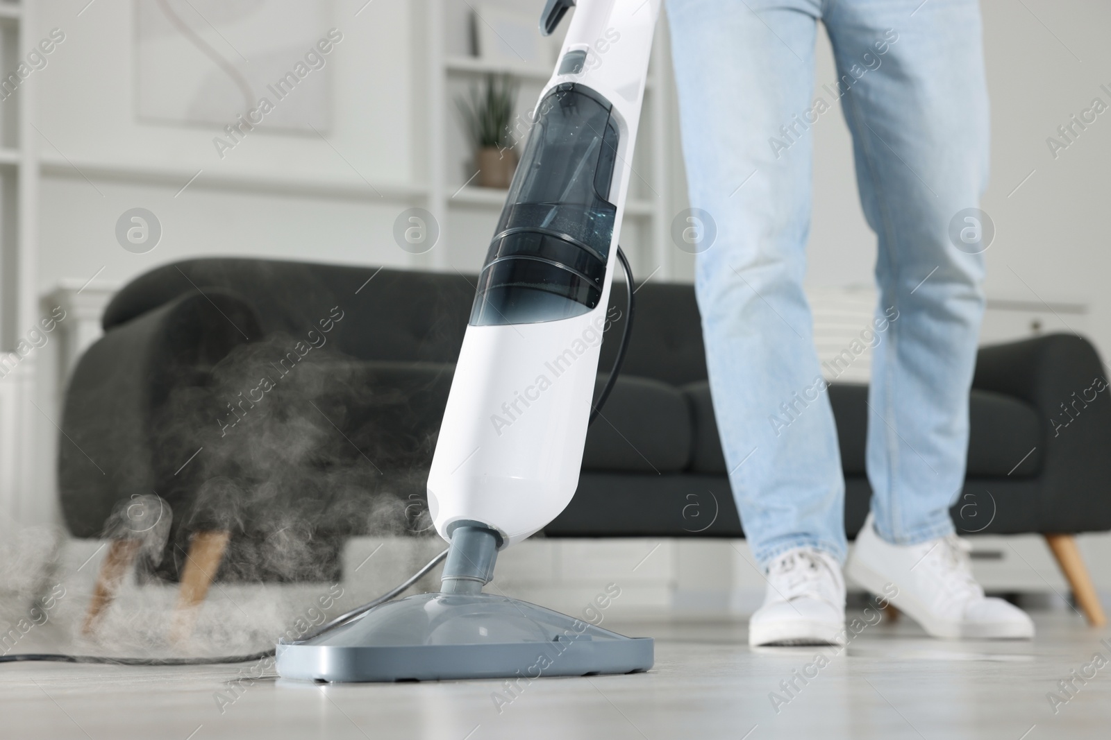 Photo of Man cleaning floor with steam mop at home, closeup