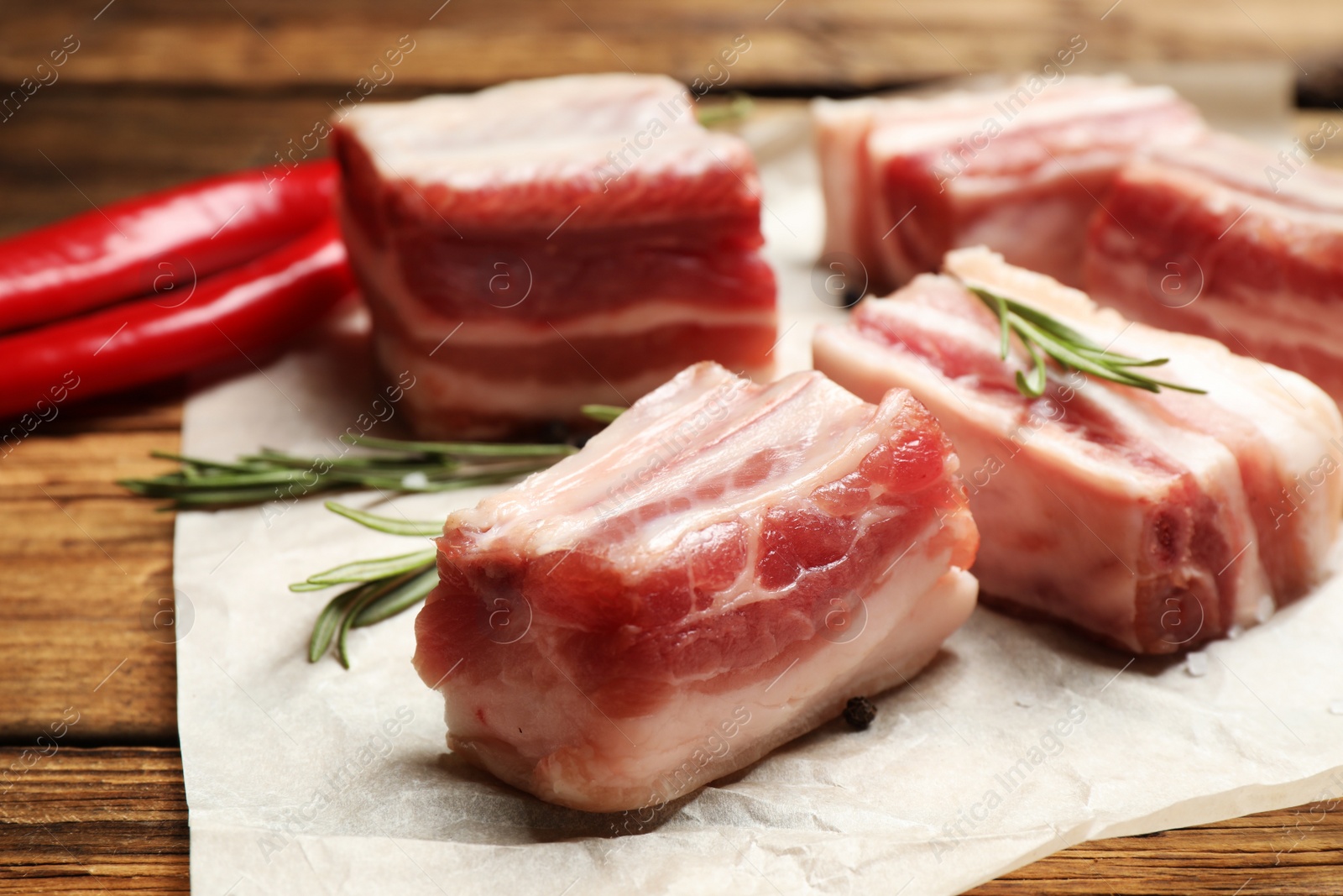 Photo of Raw ribs with rosemary on wooden table, closeup