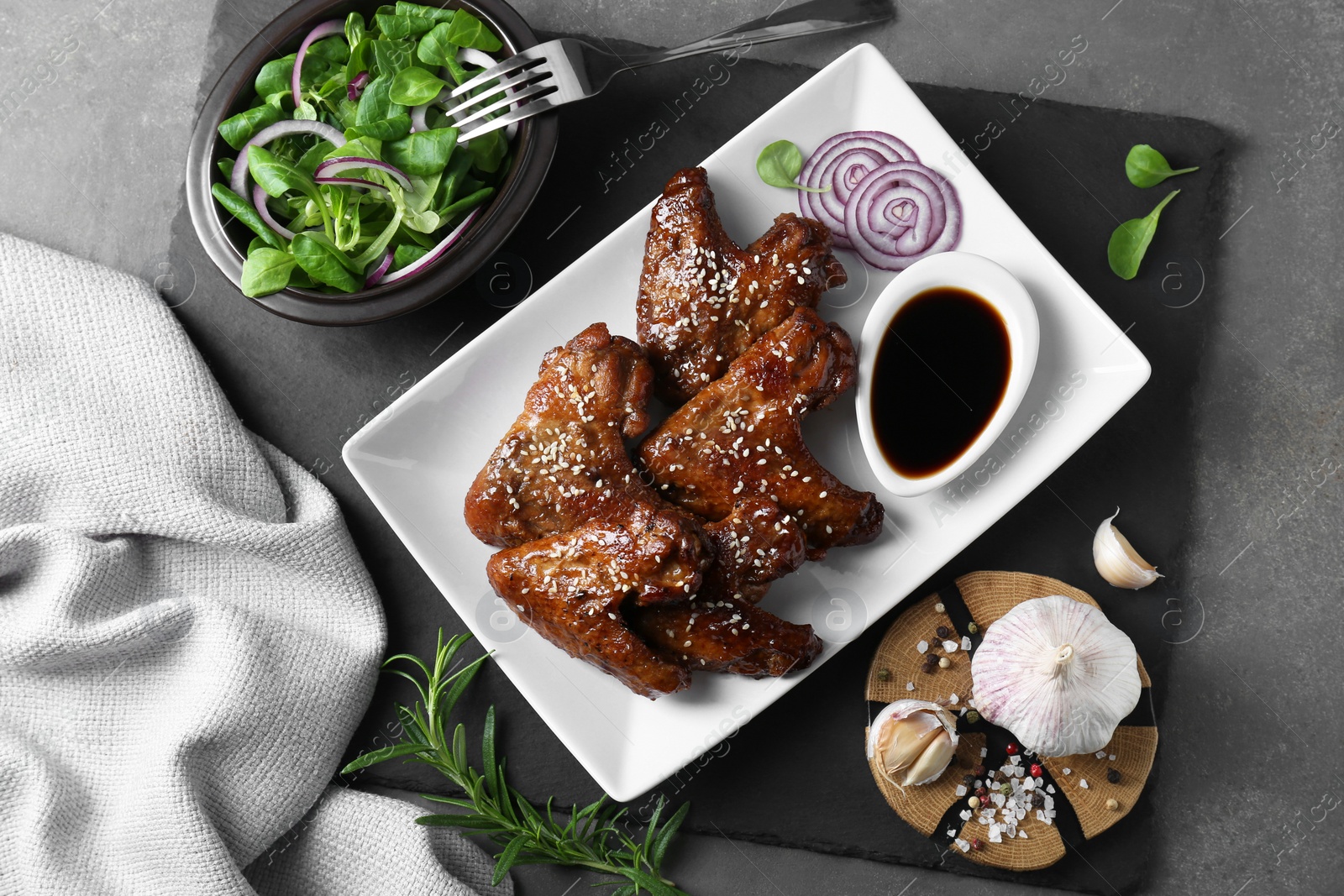 Photo of Chicken wings glazed with soy sauce served on grey table, flat lay