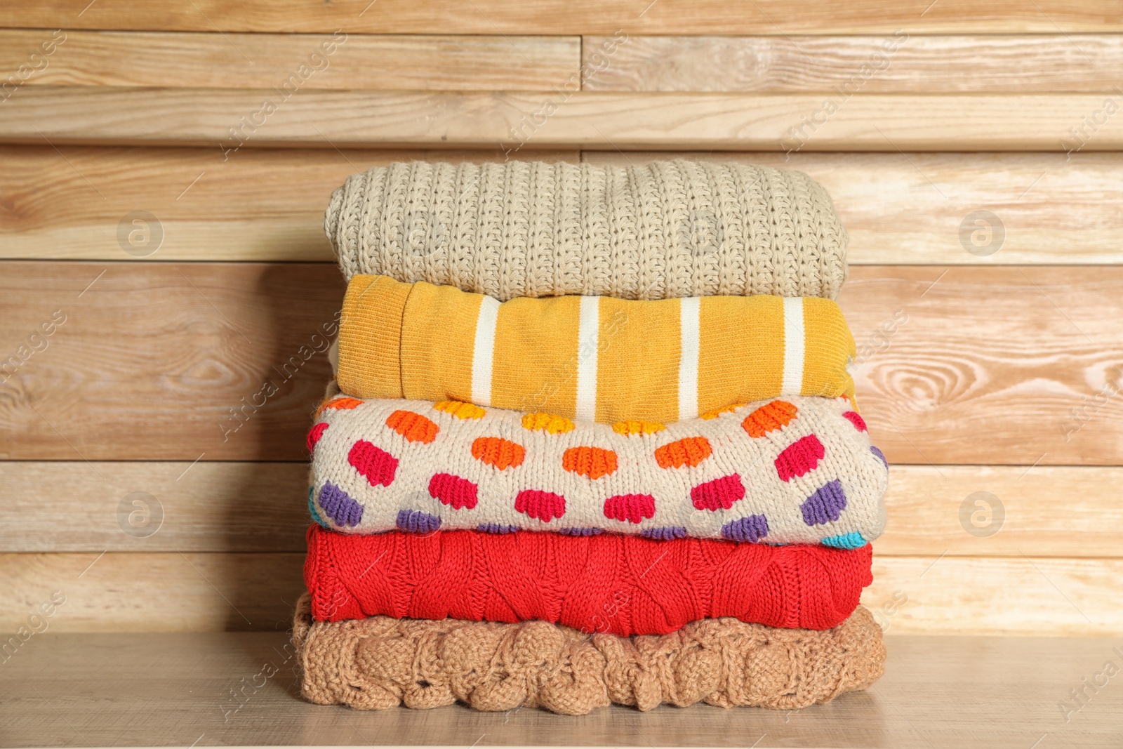 Photo of Stack of winter clothes against wooden background