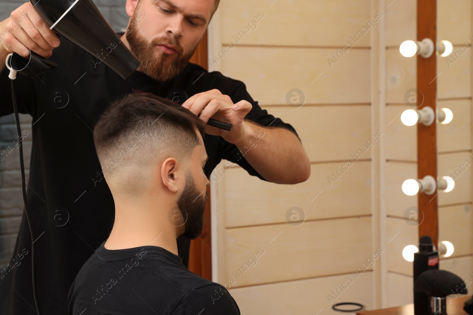 Photo of Professional hairdresser working with bearded client in barbershop