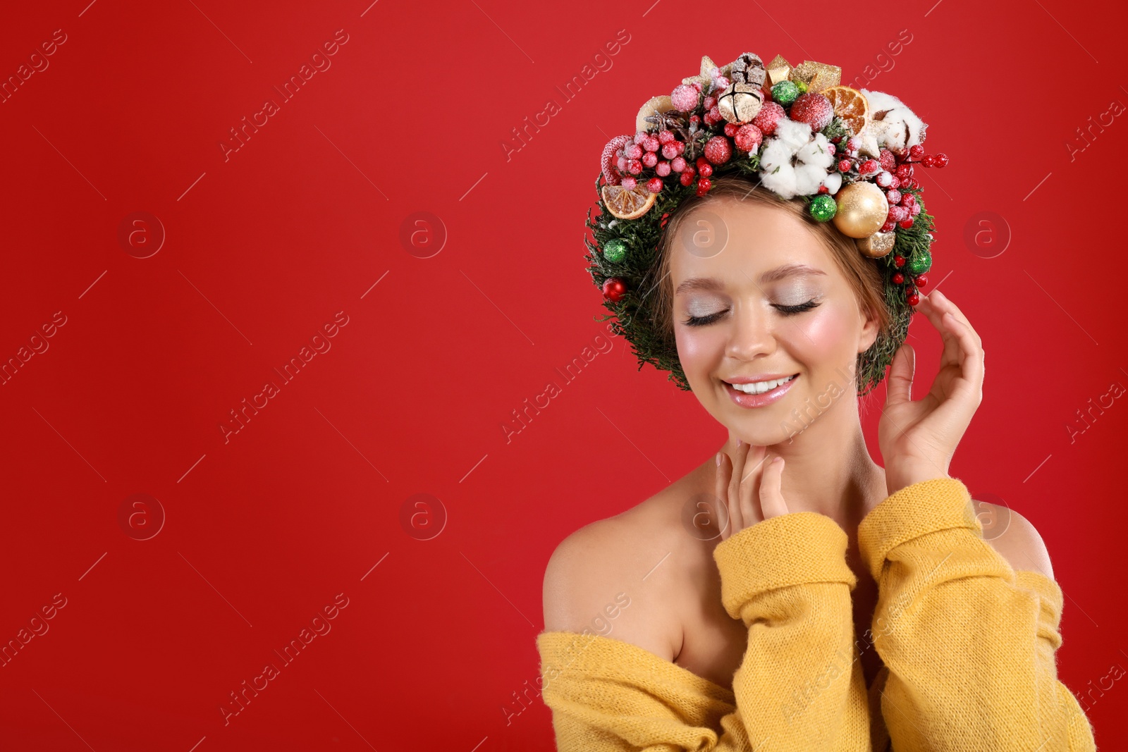 Photo of Beautiful young woman wearing Christmas wreath on red background. Space for text