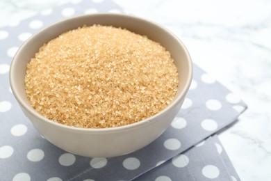 Photo of Brown sugar in bowl on white marble table, closeup. Space for text