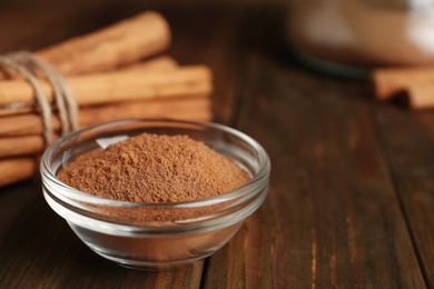 Photo of Cinnamon sticks and powder on wooden table, closeup. Space for text