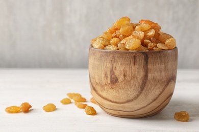 Bowl with raisins on table, space for text. Dried fruit as healthy snack