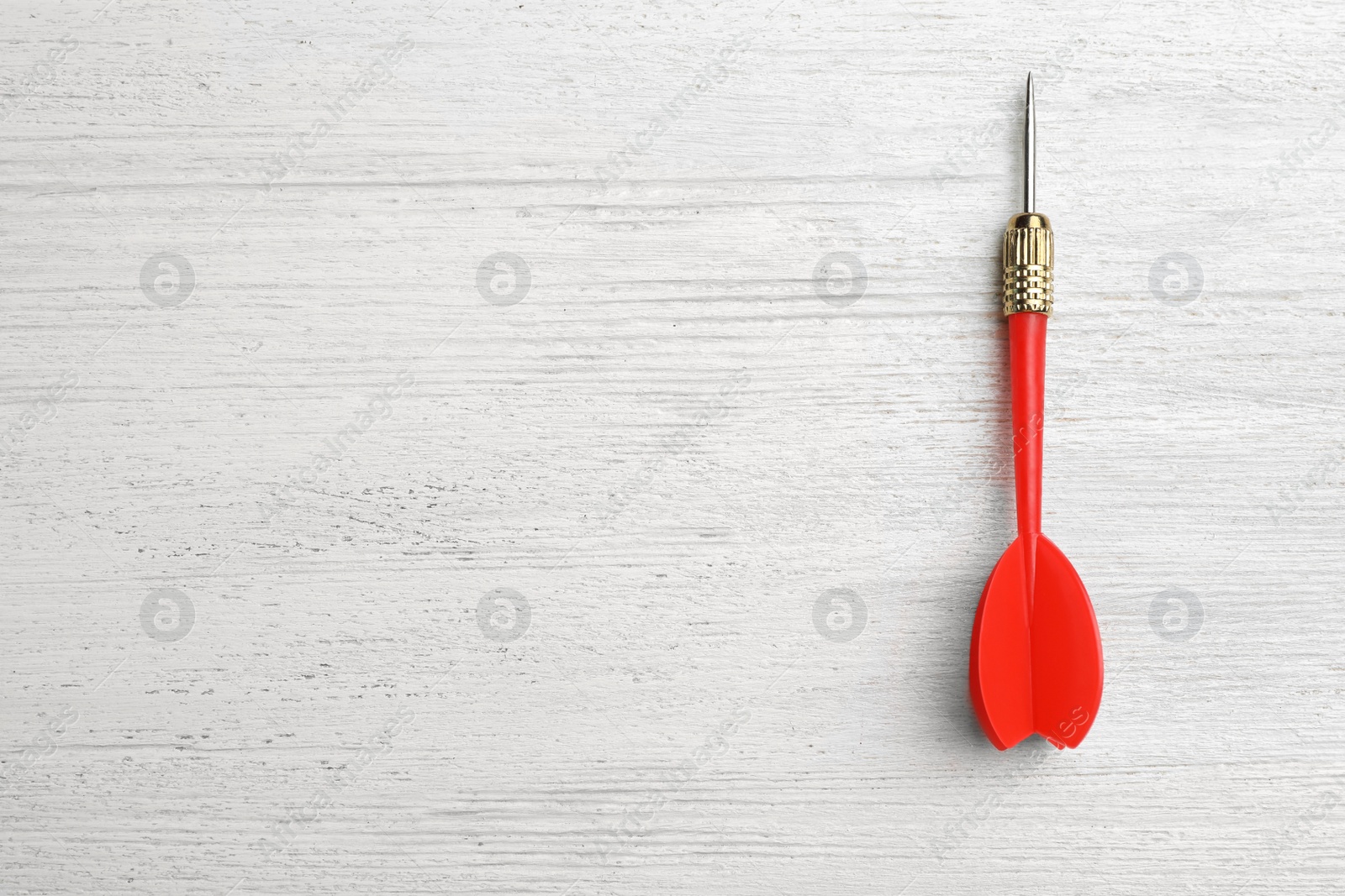 Photo of Red dart arrow on white wooden table, top view with space for text