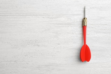 Photo of Red dart arrow on white wooden table, top view with space for text