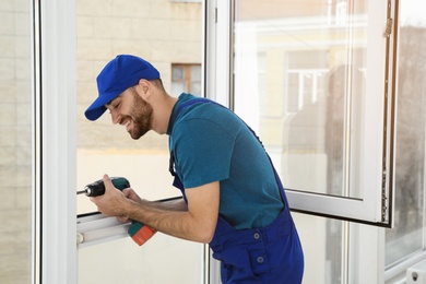 Construction worker using drill while installing window indoors