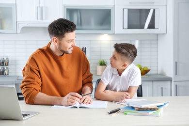 Dad helping his son with homework in kitchen