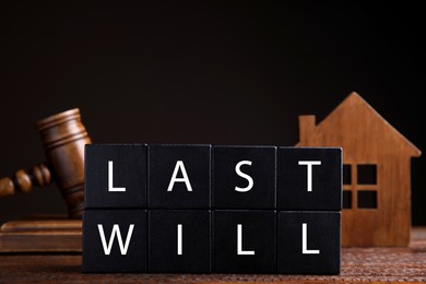 Black cubes with words Last Will on wooden table against dark background