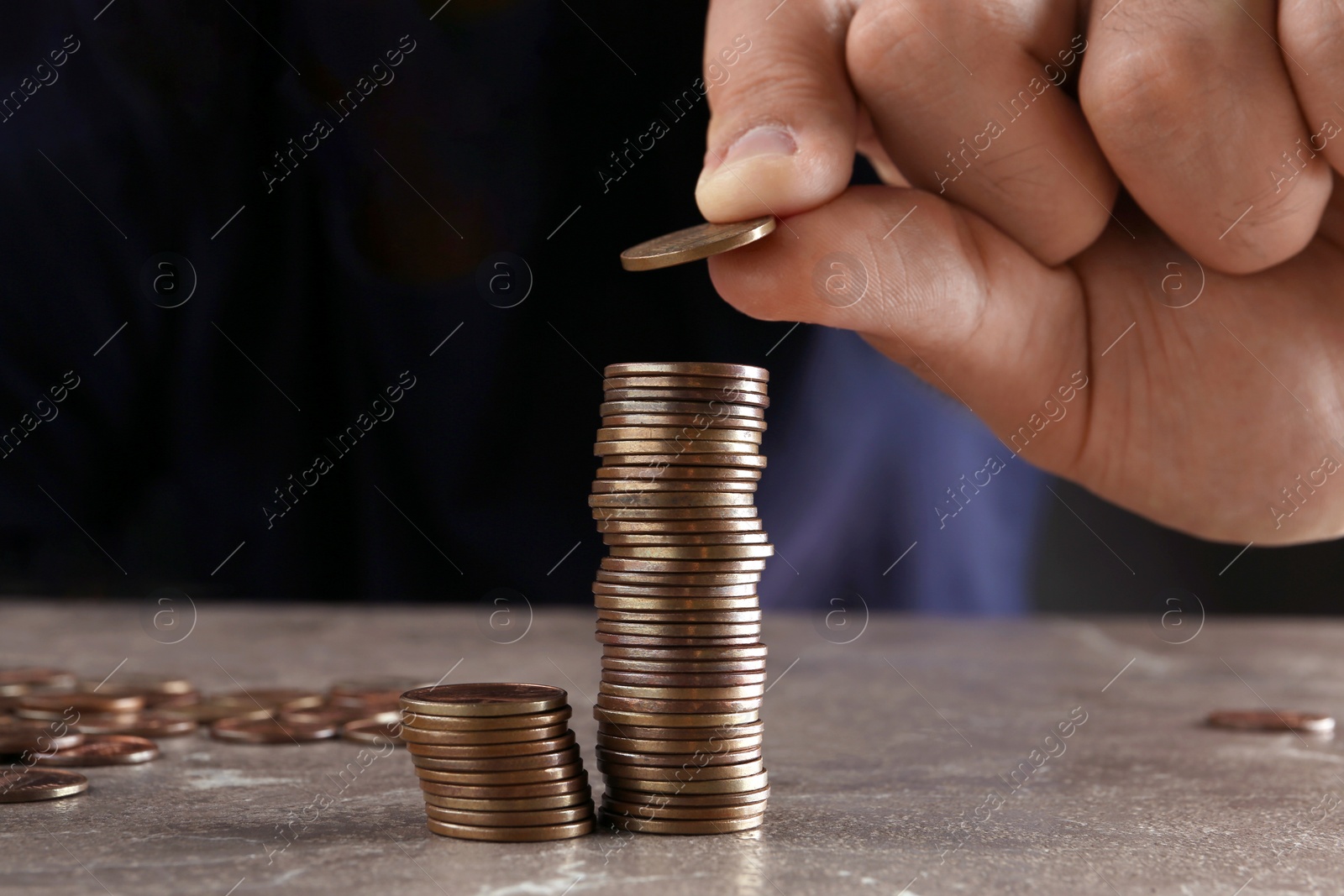 Photo of Man stacking coins on brown marble table, closeup