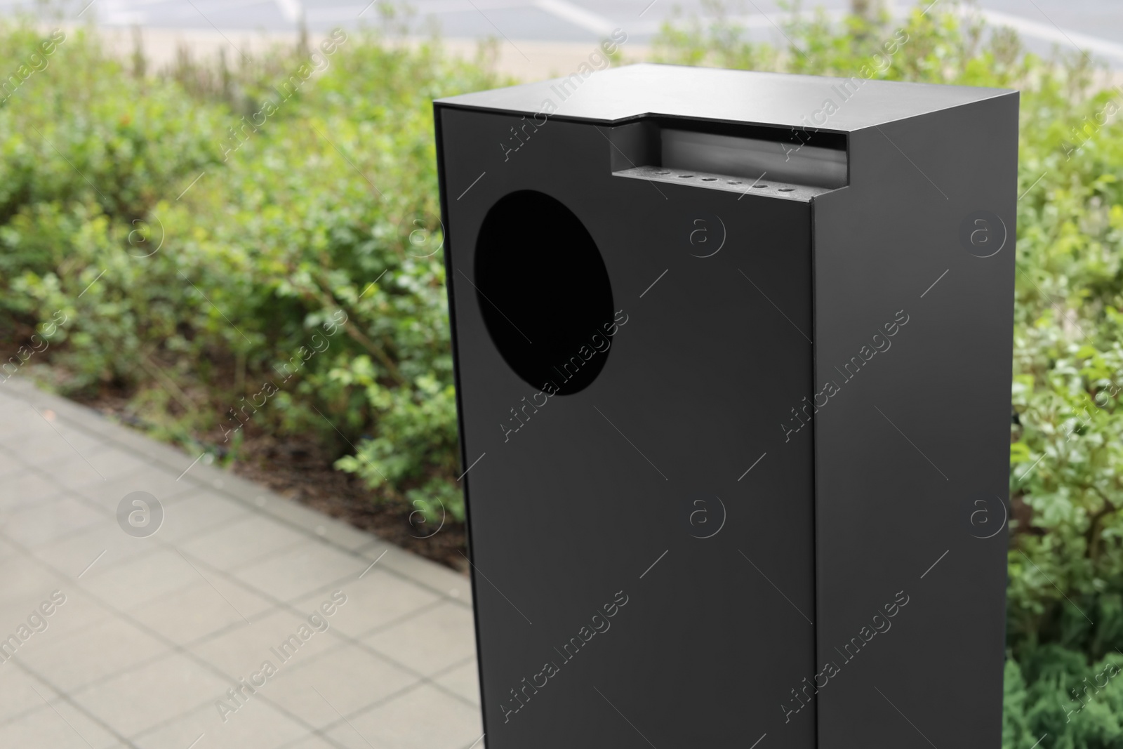 Photo of Grey trash bin in park, closeup. Space for text