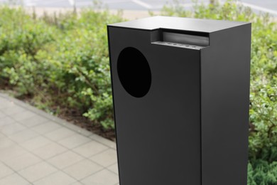 Photo of Grey trash bin in park, closeup. Space for text