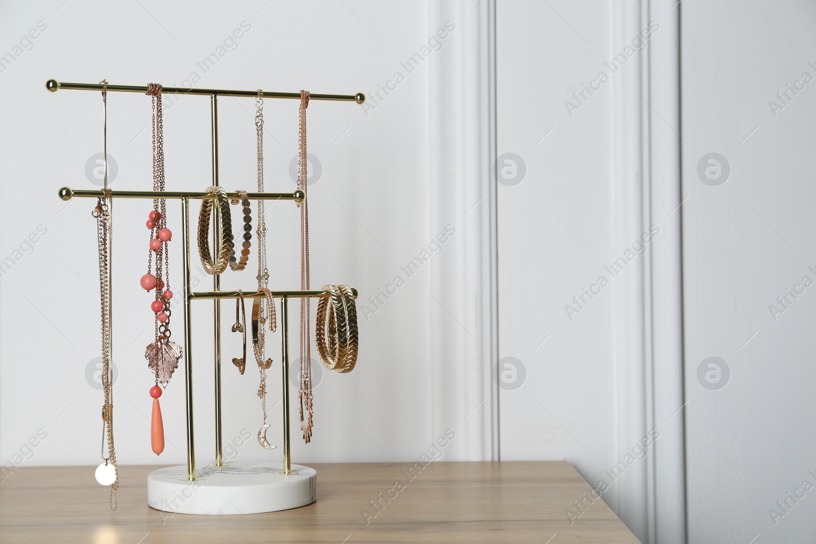 Photo of Interior element. Holder with set of luxurious jewelry on wooden table. Space for text