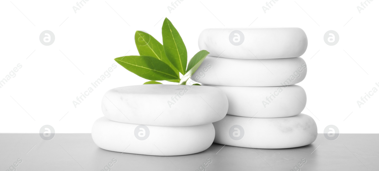 Photo of Spa stones with green branch on table against white background