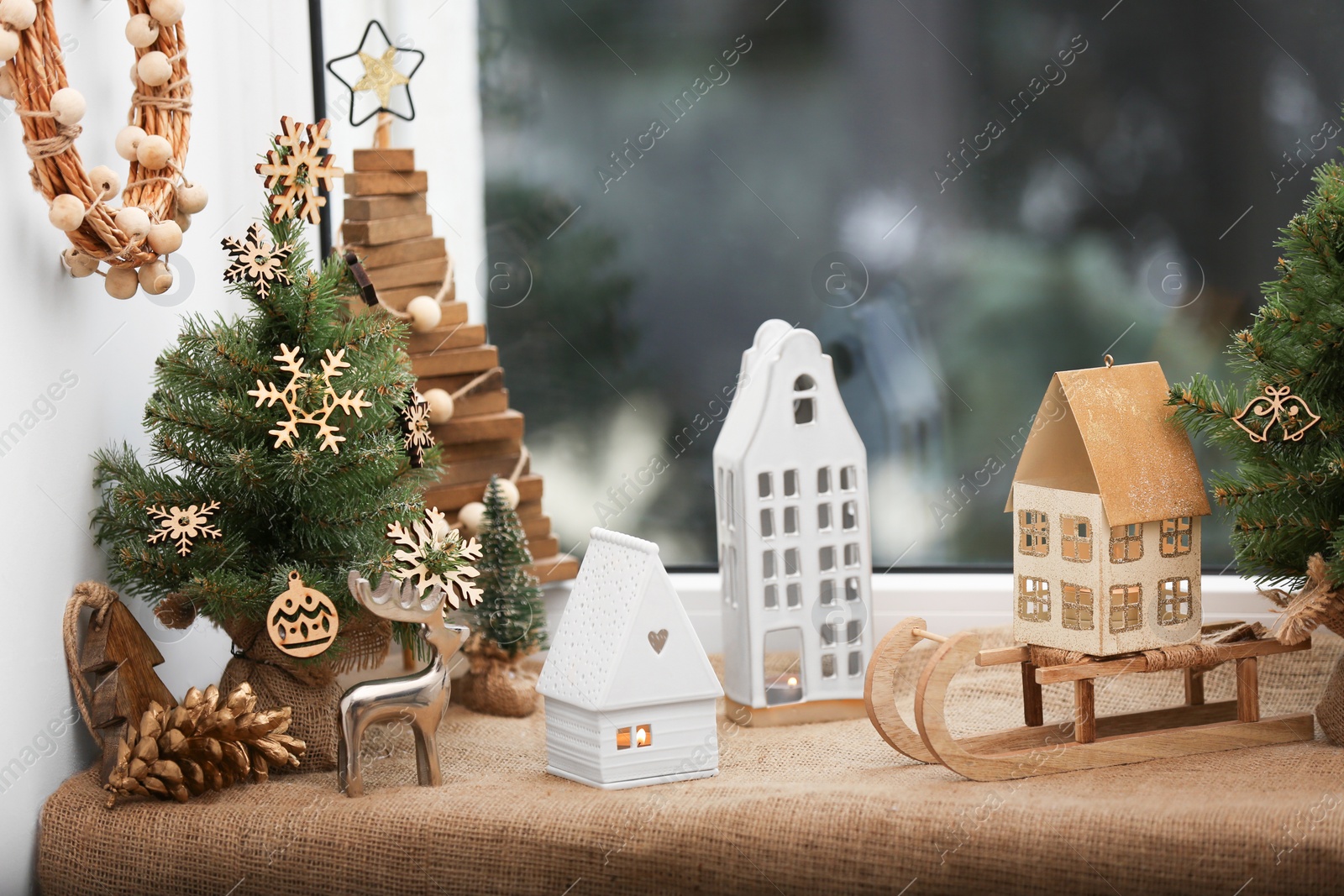 Photo of Beautiful window sill decorated for Christmas with small houses and fir trees indoors