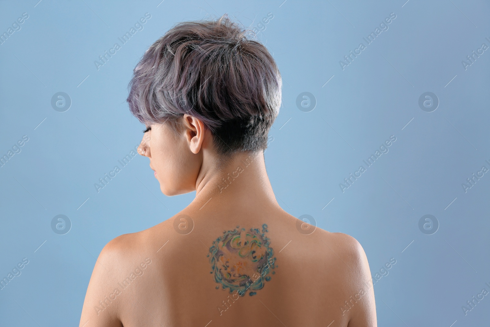 Photo of Beautiful tattoo on female back against color background