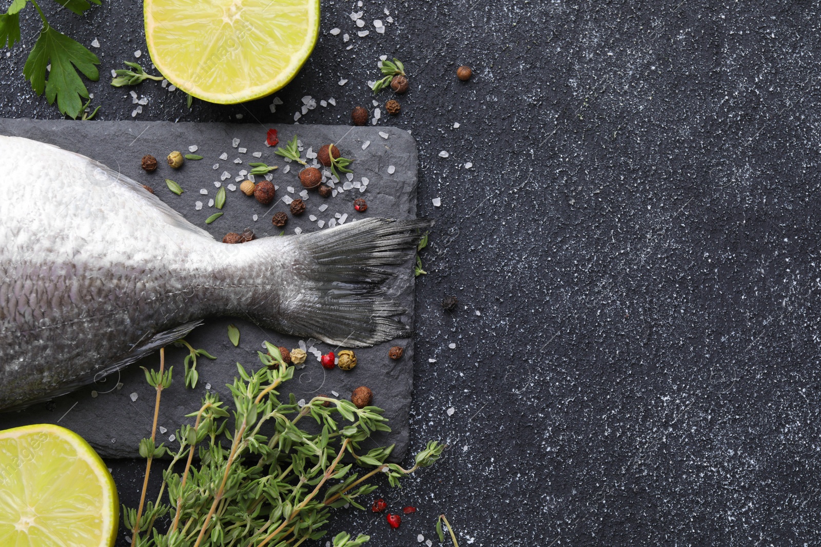 Photo of Fresh dorado fish and ingredients on black table, flat lay. Space for text