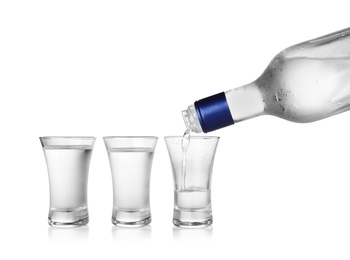 Photo of Pouring cold vodka into shot glass on white background