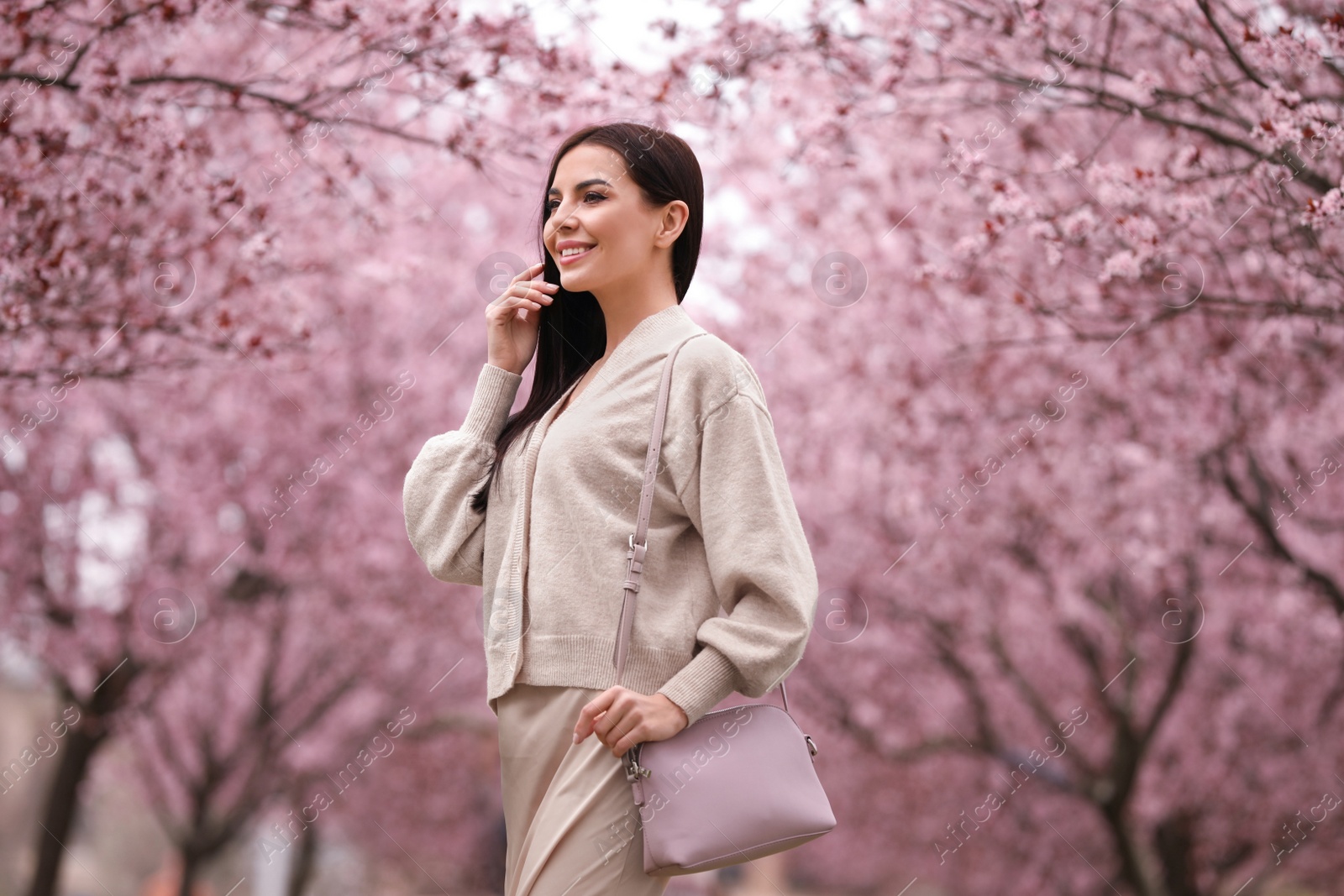 Photo of Pretty young woman in park with blooming trees. Spring look