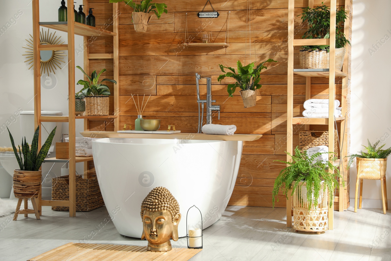 Photo of Stylish bathroom interior with white tub and green houseplants near wooden wall. Idea for design